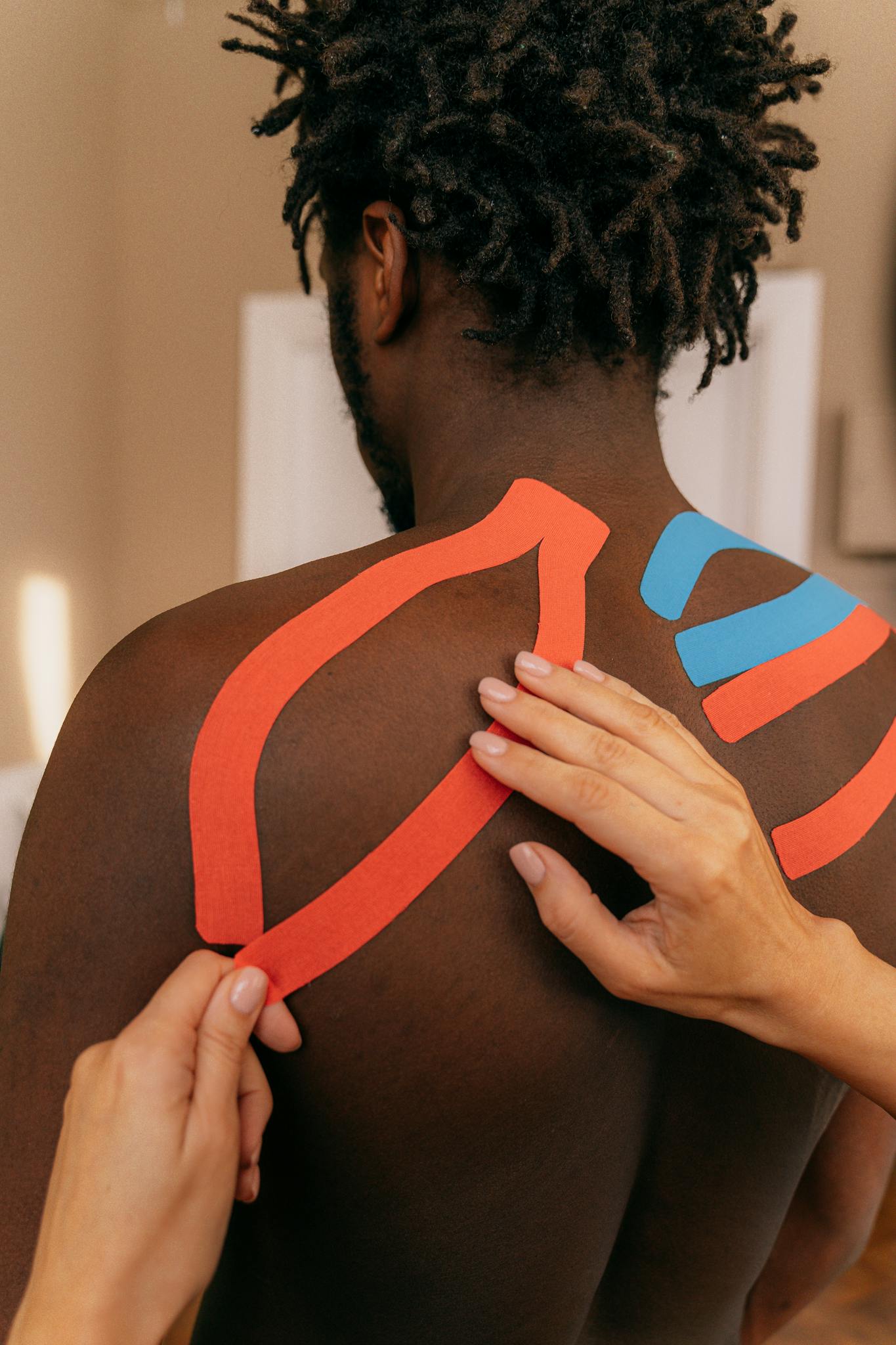 Close up of kinesio tape application on a man's shoulder for pain relief therapy.